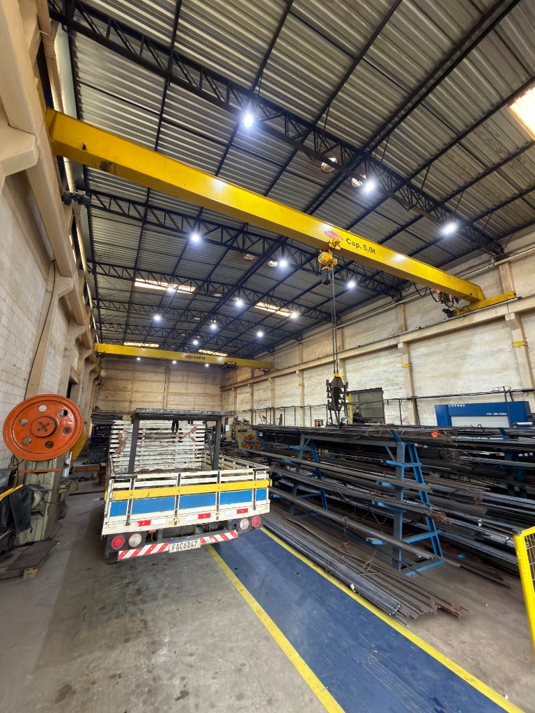 Estoque organizado de barras de aço e ferro no galpão industrial da SteelForte com ponte rolante de 5 toneladas