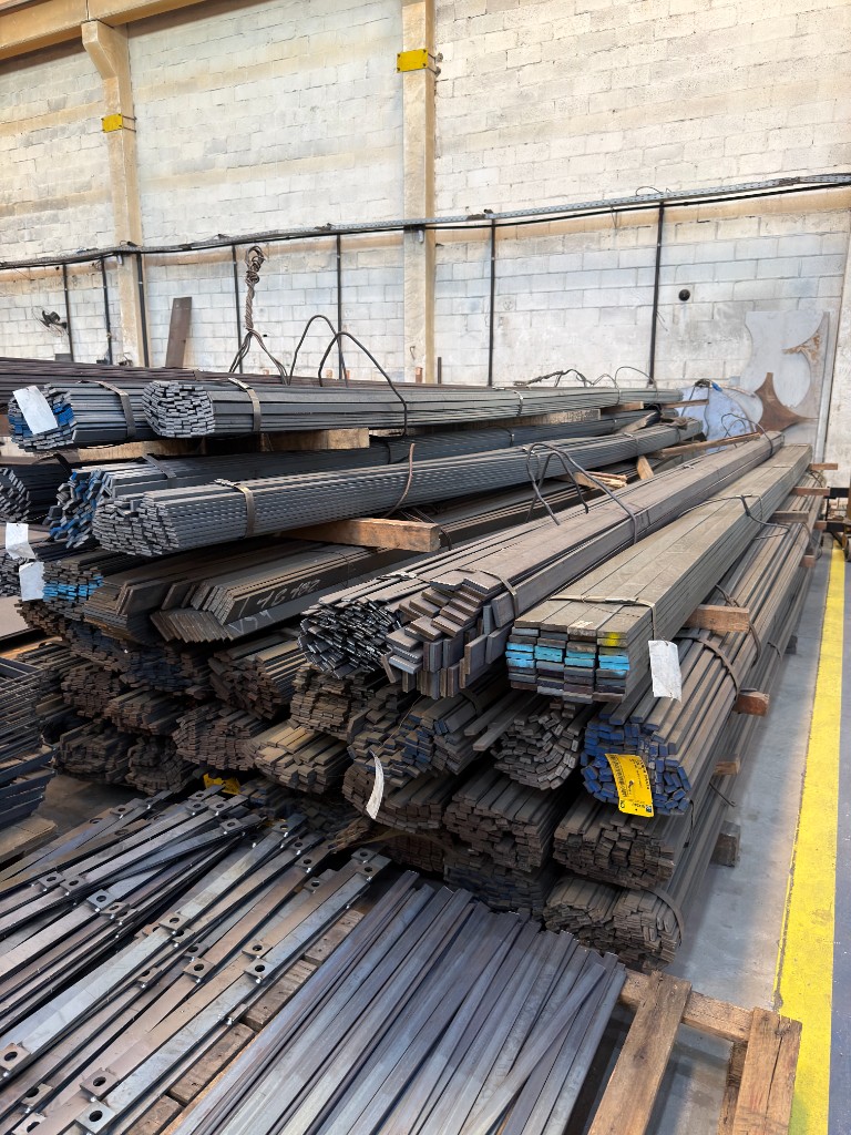 Estoque organizado de chapas, barras e materiais metálicos no galpão industrial da SteelForte